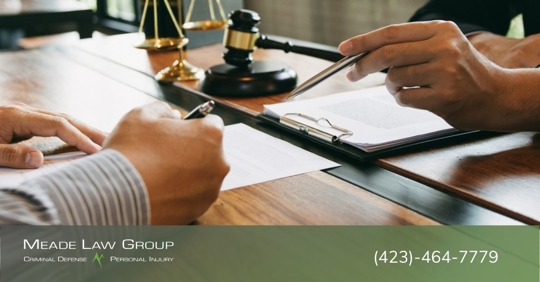 Man signing a contract with a lawyer holding a pen near the contract